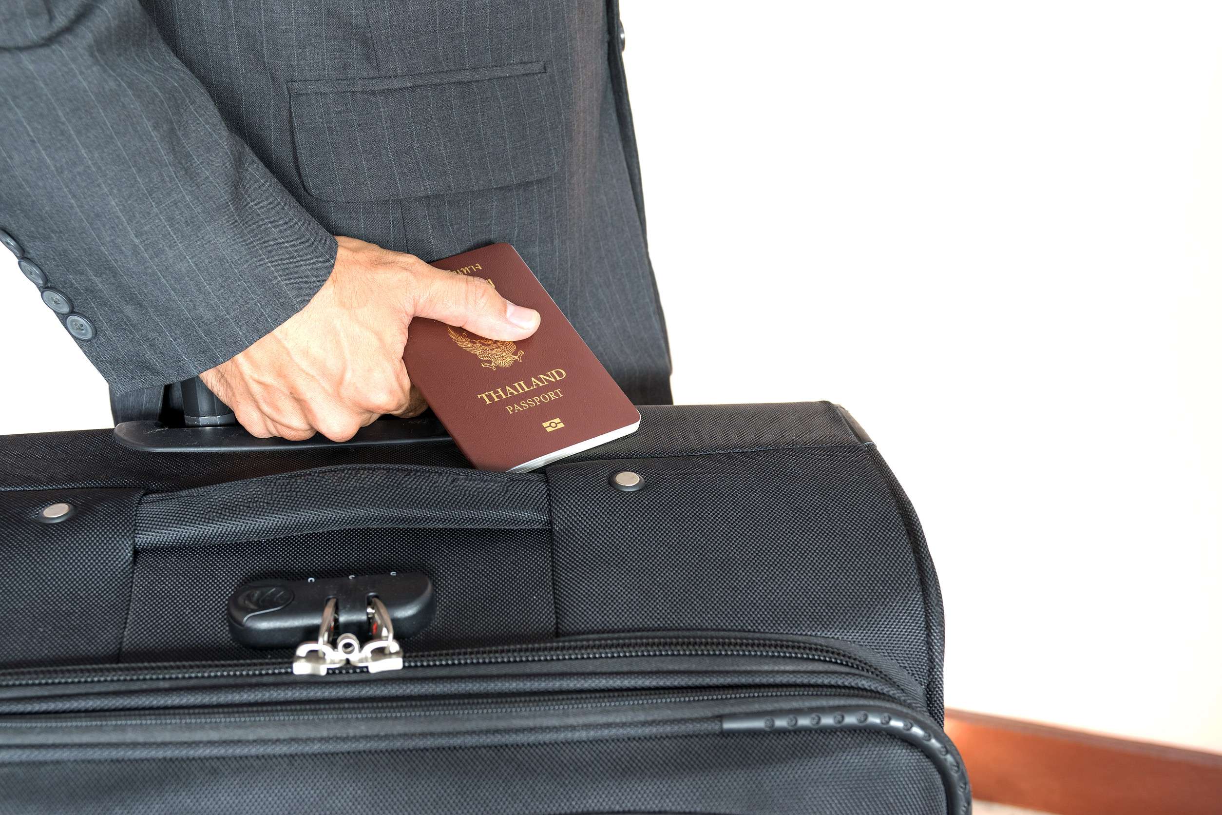Businessman Holding The Passport Of Thailand With The Black Suitcase