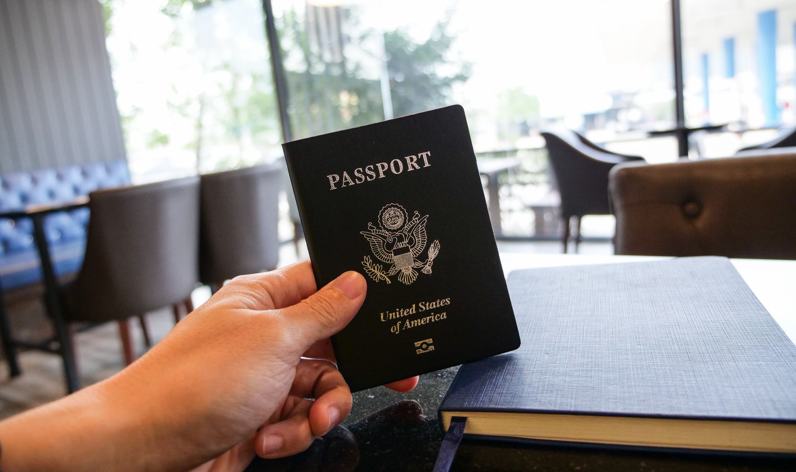 Hand Holding Passport And Restaurant Background Travel Concept